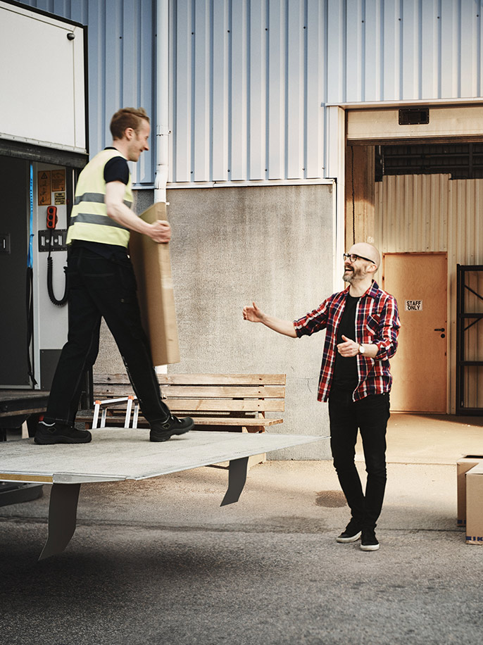 A delivery driver unloads a box to a customer.