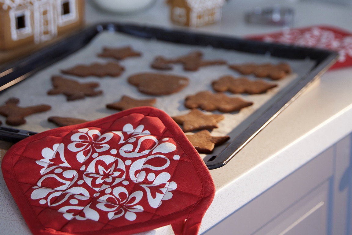 Oven mitt on a tray of cookies.